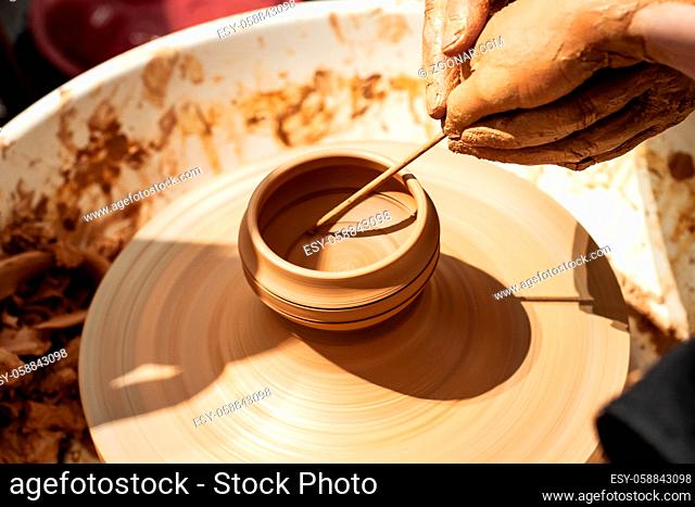 Expert potter teach a child to work on potter wheel. Closeup of dirty hands