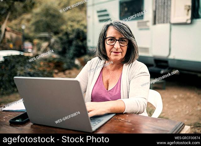 Camping woman using laptop sitting at table