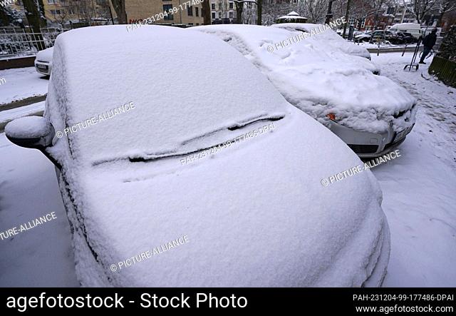 04 December 2023, Hamburg: A thick layer of snow lies on parked vehicles in the Eimsbüttel district. The German Weather Service is expecting a total of up to...