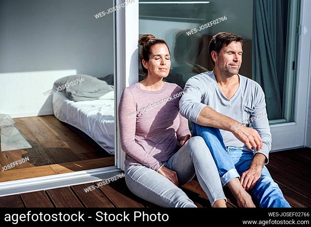Mature man and woman with eyes closed sitting against on sunny day