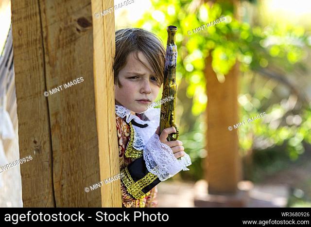 Young boy dressed as a pirate holding long pistol