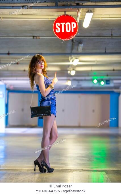 Attractive woman and STOP sign in empty underground parking-lot