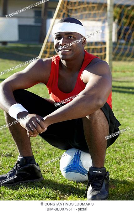 Black man sitting on soccer ball