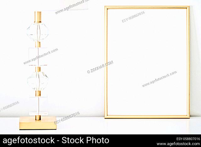 Golden frame for art, poster or photo in white interior, home decor concept