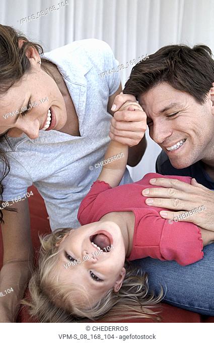 Close-up of a mid adult couple tickling their daughter