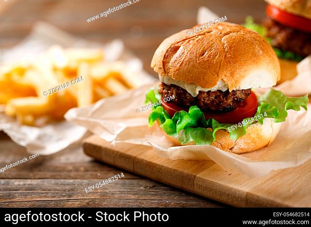 Homemade tasty burger and french fries on wooden table