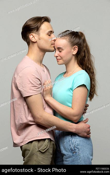 Studio portrait affectionate, tender young couple hugging