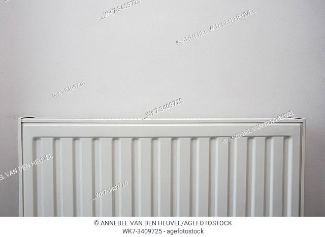 A White heating radiator on the white wall, modern design close-up