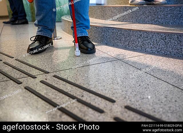14 November 2022, Saxony, Görlitz: A blind person with a long cane stands in front of the newly installed floor guidance system for blind and visually impaired...