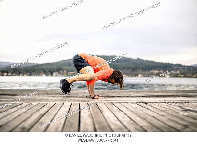 Athlete exercising on wooden deck at the lakeshore