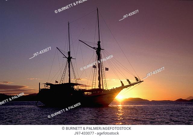 The liveaboard dive boat, Komodo Dancer, silhouetted against a sun setting sky, Komodo Islands, Indonesia, Indo-Pacific