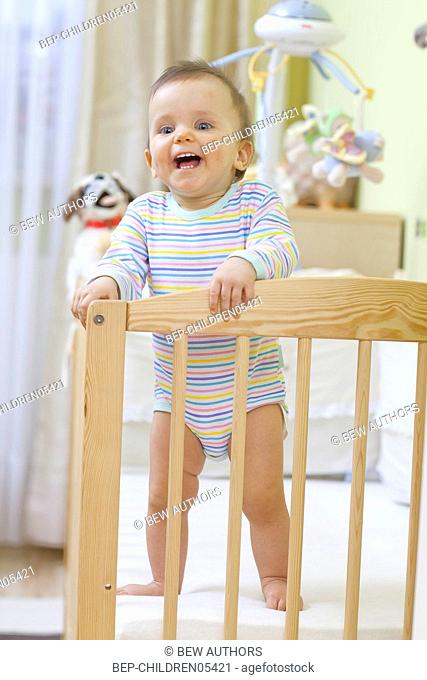 Child sitting in baby cot