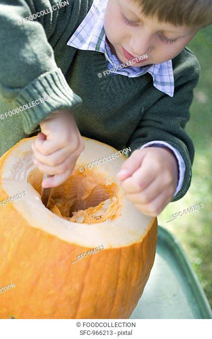 Small boy hollowing out pumpkin with spoon