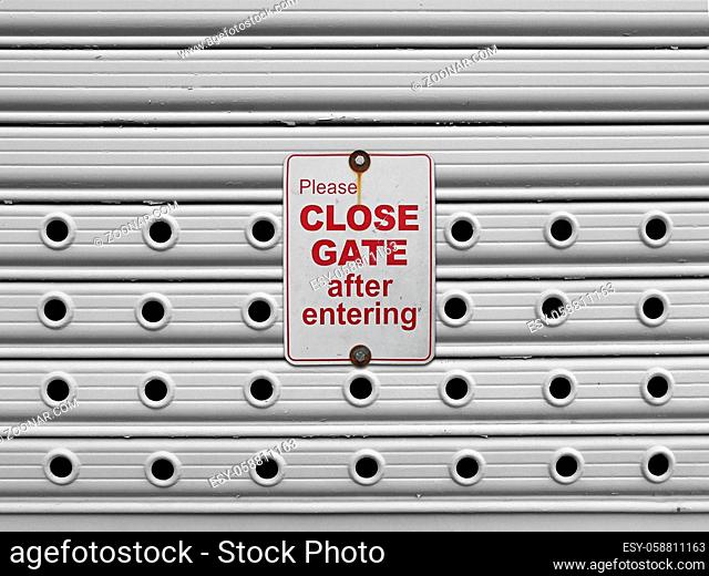 please close sign on a light grey painted perforated roll up gates background