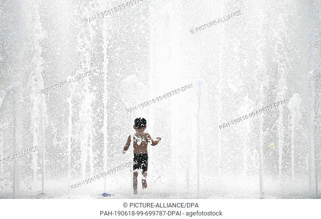 18 June 2019, Hessen, Frankfurt/Main: A little boy has a lot of fun in summer temperatures in the fountain of the Walther-von-Cronberg-Platz in the district of...