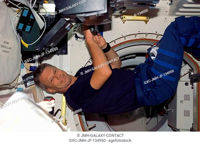 Astronaut Piers J. Sellers, STS-121 mission specialist, uses a computer near a hatch on the middeck of the Space Shuttle Discovery while docked with the...
