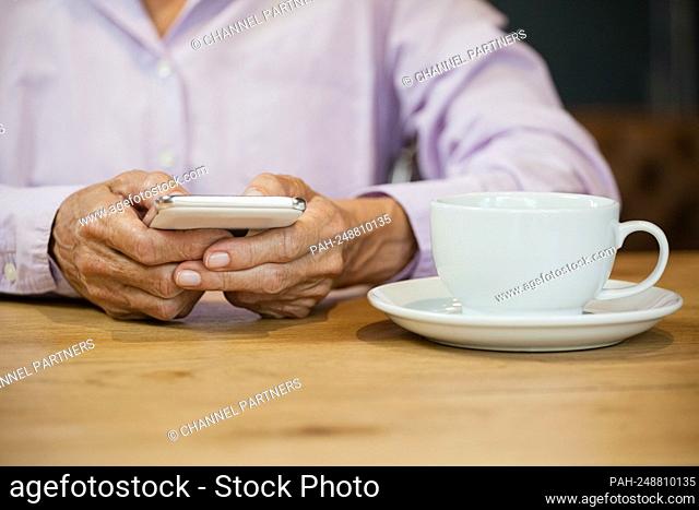 Midsection of senior woman using smart phone at table in cafe || Model approval available