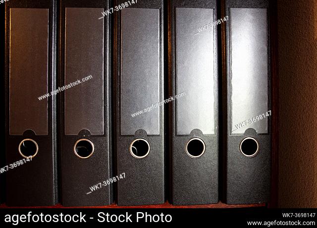 four black ring binders on a bookshelf for office or administration, business concept background close up