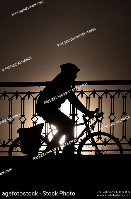 04 December 2023, Saxony, Dresden: A cyclist is riding on the Marienbrücke bridge in the morning sunshine. Photo: Robert Michael/dpa