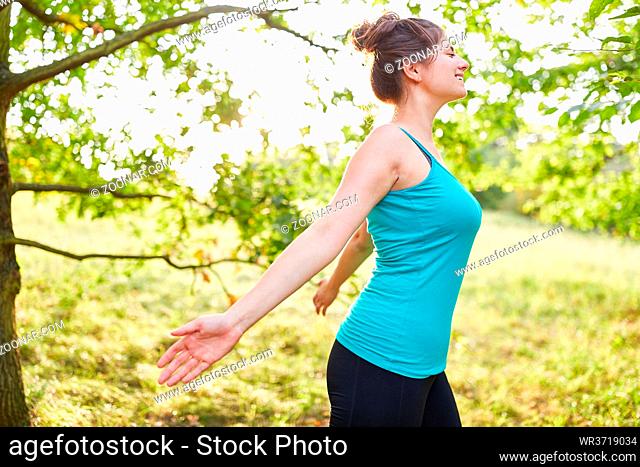 Glückliche junge Frau atmet frische Luft beim Stressabbau Training in der Natur