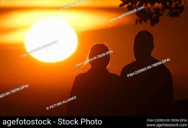 05 September 2023, Lower Saxony, Hanover: A couple sits on the Kronsberg at sunrise. Photo: Julian Stratenschulte/dpa. - Hanover/Lower Saxony/Germany
