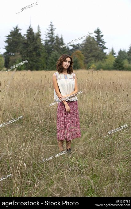 Portrait of seventeen year old girl standing in field of tall grasses, Discovery Park, Seattle, Washington