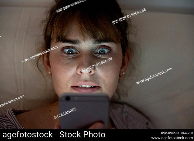 Woman at night admiring her lit smartphone. Addictive behavior