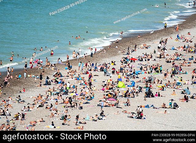 SYMBOL - 20 August 2023, France, Dieppe: Numerous people are lying on the pebble beach in the sunshine. Photo: Silas Stein/dpa