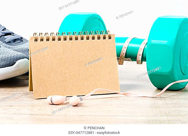 Blank diary with sneakers and dumbbells on wooden background. Weight loss, body toning concept