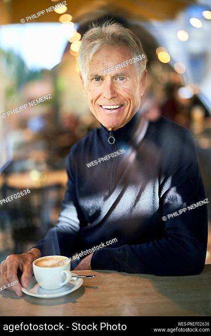 Smiling senior man with coffee cup in cafe