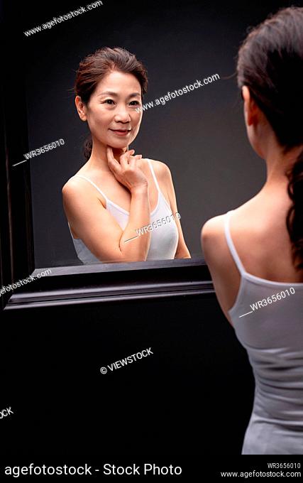 Beautiful middle-aged women enjoy herself in the mirror