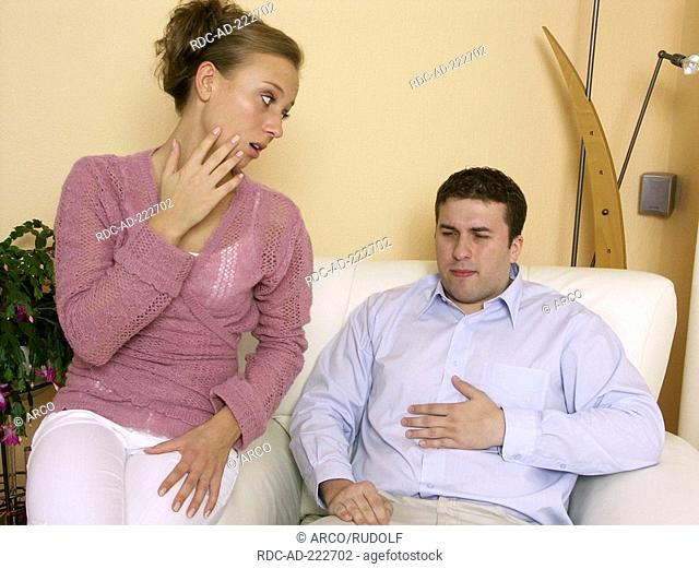Man having stomache pain, woman commiserating