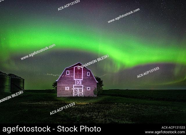 Aurora dancing over old red barn in rural Manitoba, Canada
