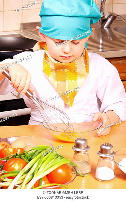 Little cook beating up eggs