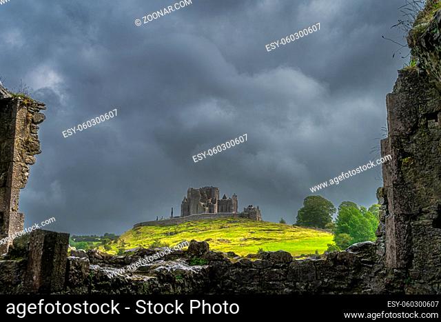 View through old ruins of Hore Abbey walls on Rock of Cashel castle with dark dramatic storm sky in the background, County Tipperary, Ireland