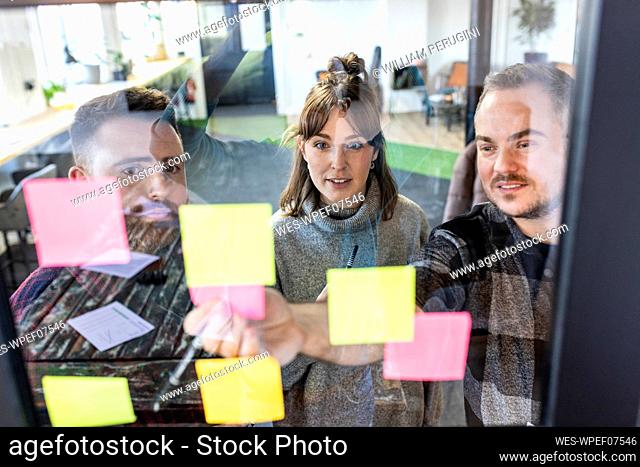 Businessman with colleagues discussing over adhesive notes
