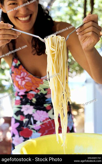 Young woman taking spaghetti out of a plastic colander