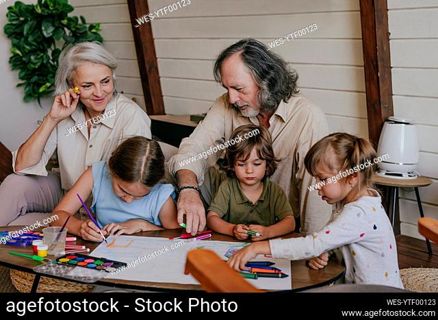 Grandparents helping kids in painting at home