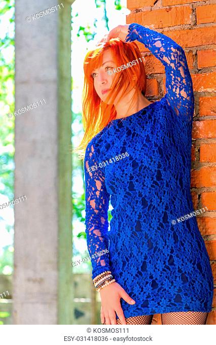 Girl 30 years in lace dress posing near the wal