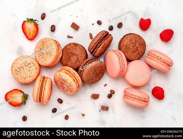 Composition with french macarons on white marble background. Top view of colorful pastel macaroons or macaron with berries, chocolate and coffee beans