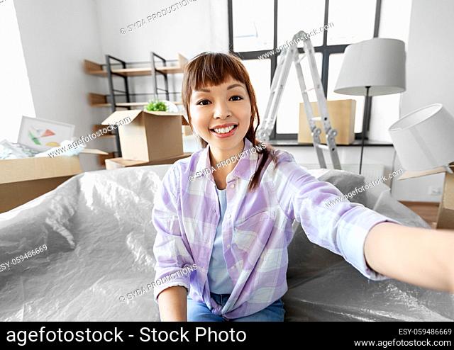 smiling asian woman taking selfie at new home