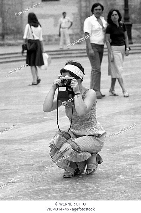 SPANIEN, VALENCIA, 15.08.1977, Seventies, black and white photo, holidays, tourism, woman takes a picture watched by a young couple, amateur photographer