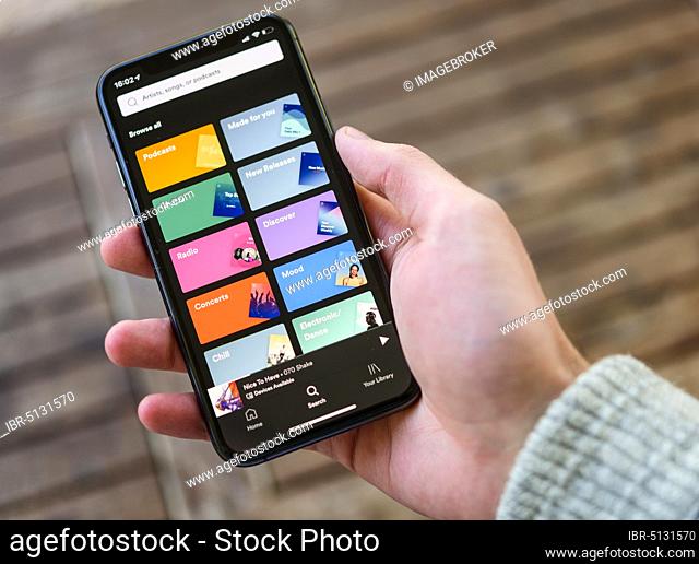 Hand holds iPhone 11 with Spotify App on display, music streaming, iOS, Smartphone, Germany, Europe
