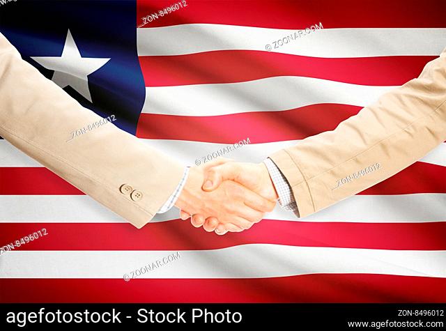 Businessmen shaking hands with flag on background - Liberia