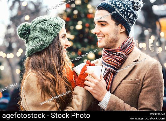 Woman and man drinking mulled wine on Christmas Market in front of tree