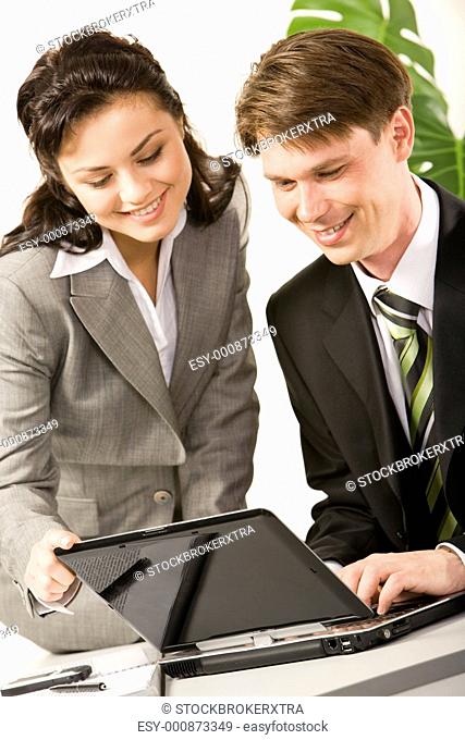 Portrait of two business partners looking at laptop monitor and discussing new project