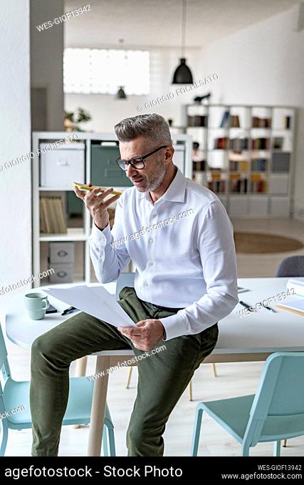 Mature businessman talking on mobile phone in office