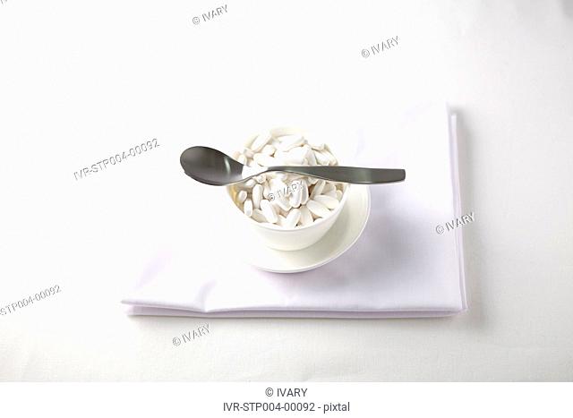 Teacup filled with white tablets with spoon on it