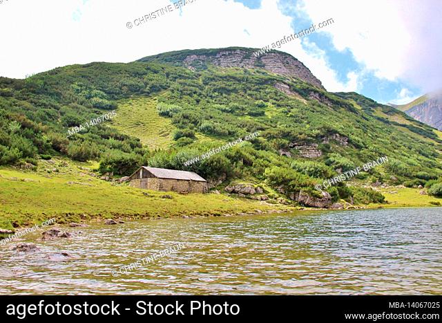 hike to the zireiner see 4 hectare mountain lake at 1799 m in the brandenberg alps, tyrol, münster municipality, old stone-walled alpine hut with shingle roof