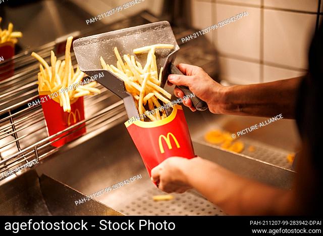 02 December 2021, Bavaria, Munich: An employee fills a bag with French fries at a branch of the McDonald's fast food chain on Martin-Luther-Strasse in Giesing